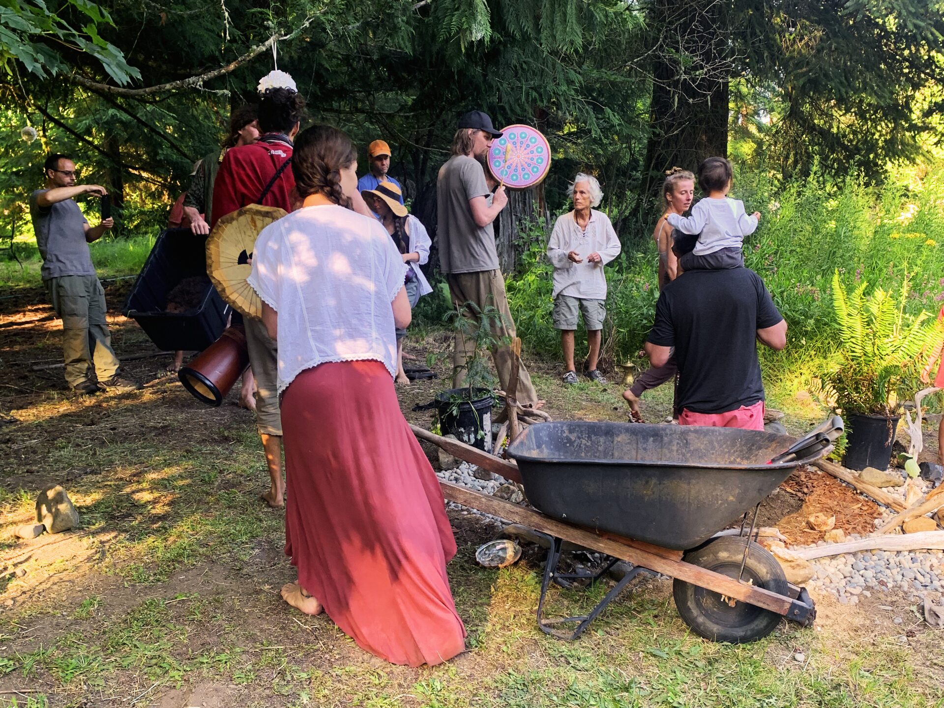Community gathering at Wo-Man-I-Fest, drums and golden light in the forest